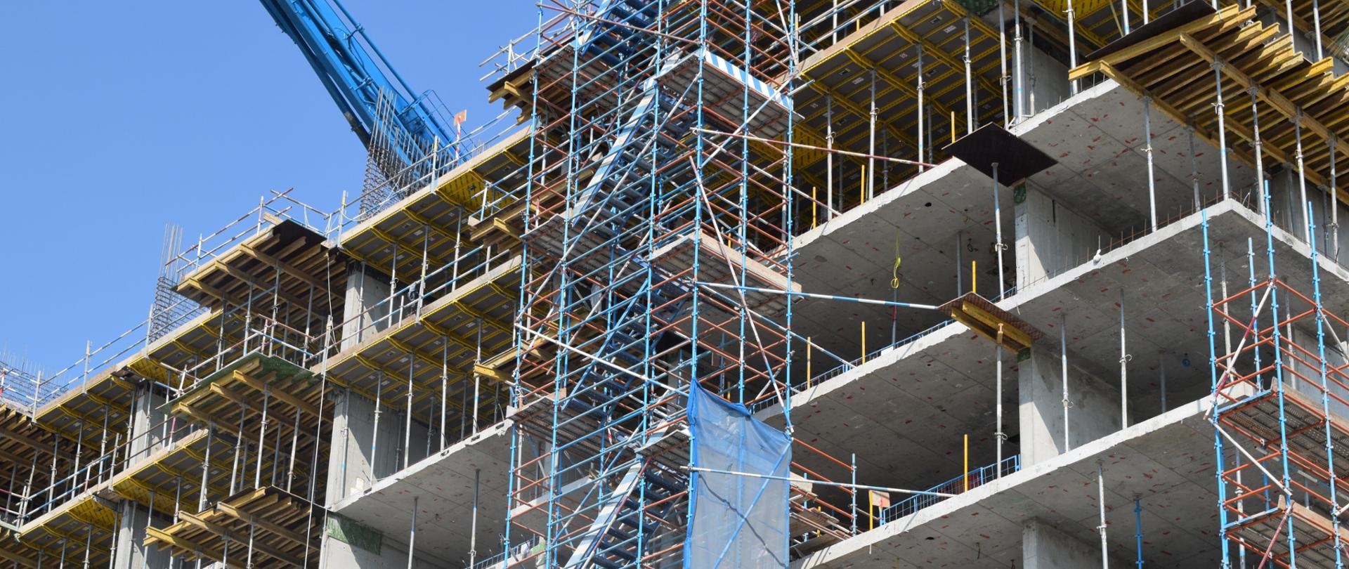 na zdjęciu: blok mieszkaniowy w budowie, widać rusztowania i konstrukcję 