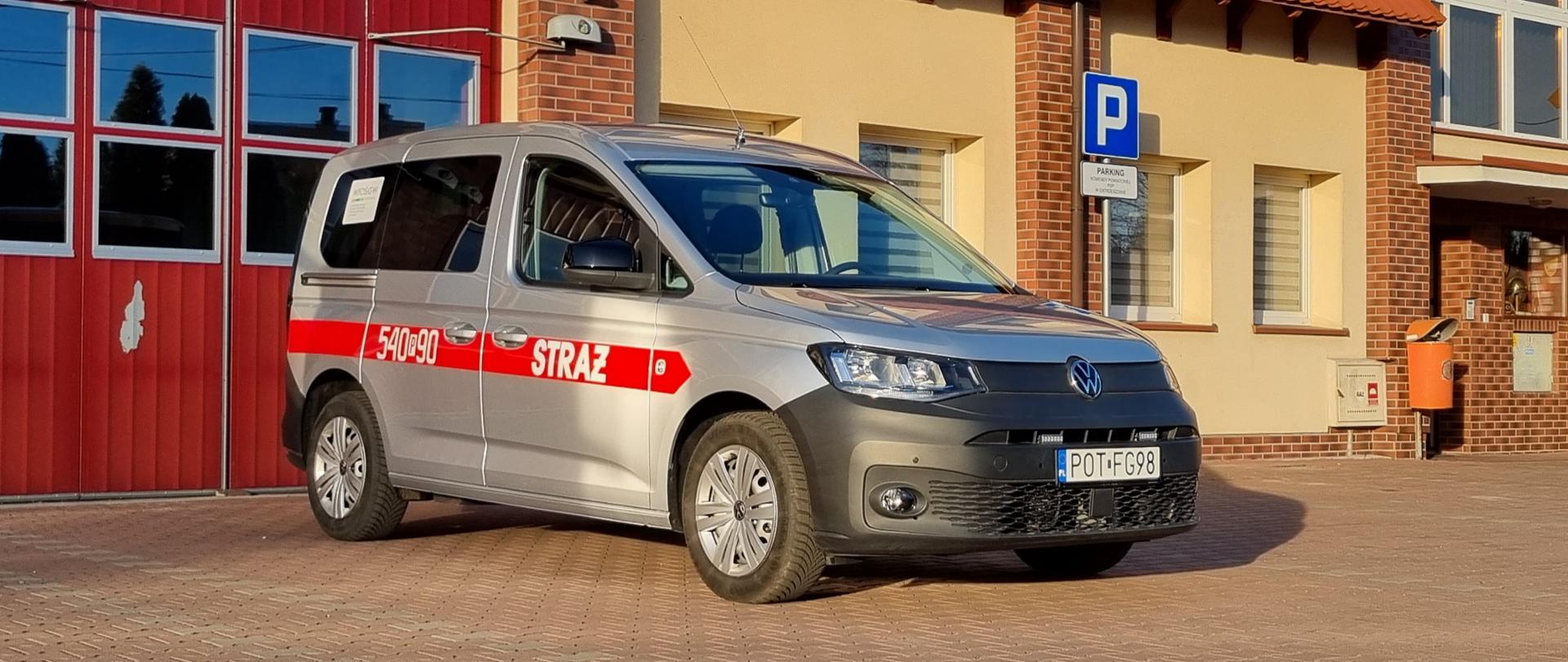Samochód lekki VW Caddy w kolorze srebrnym przed strażnicą.