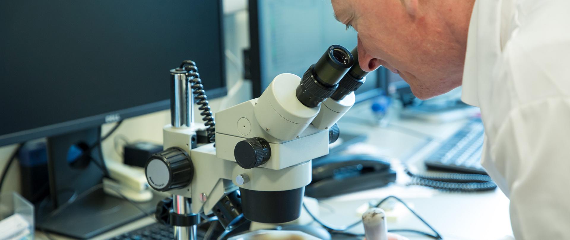 Naukowiec, który bada próbkę pod mikroskopem
