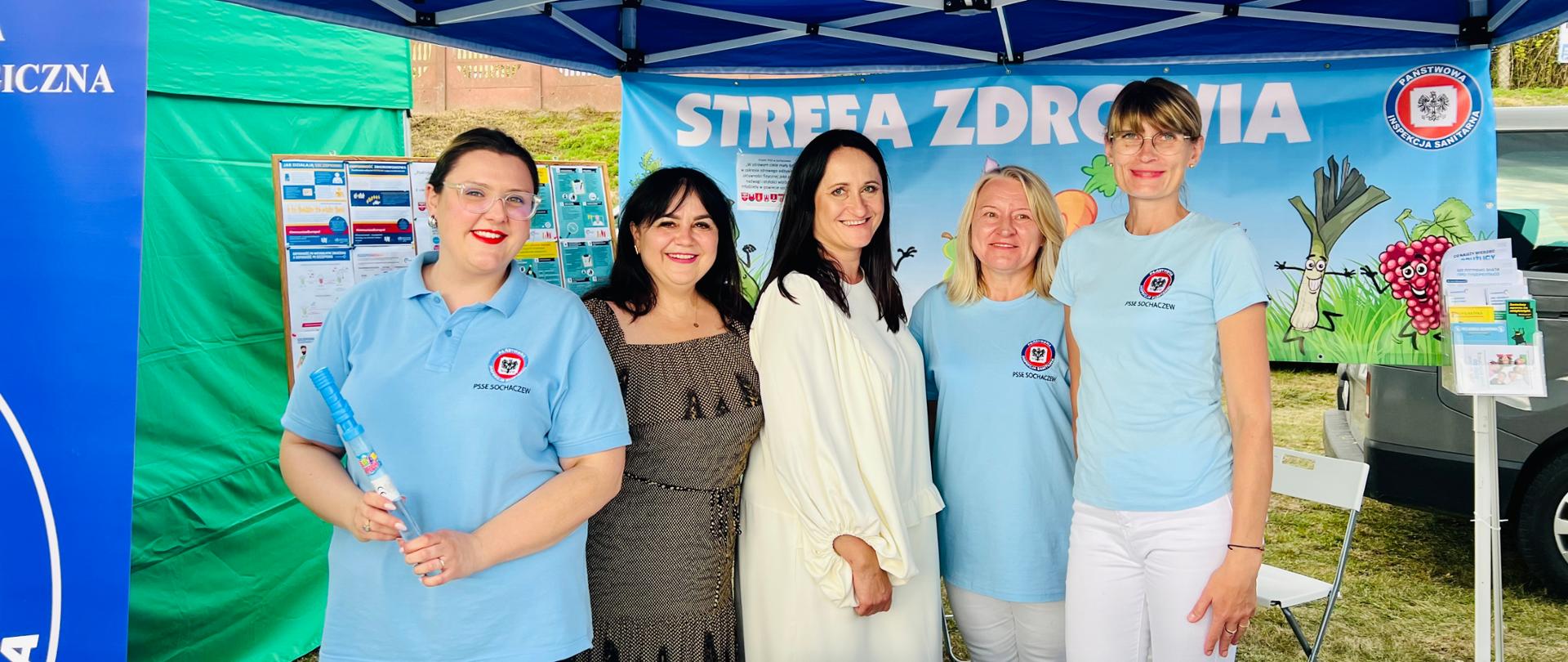 Stoisko PSSE w Sochaczewie podczas Dożynek Powiatowych w Młodzieszynie 17.09.2023. Pracownicy stoją na zdjęciu z Inspektorem oraz Wójt Gminy Młodzieszyn.