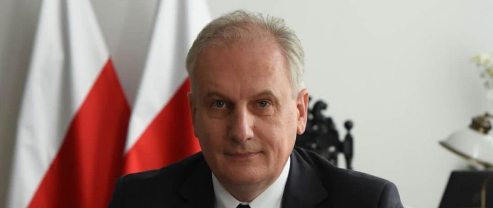 Wojewoda Pomorski w swoim gabinecie. W tle godła oraz flaga RP.