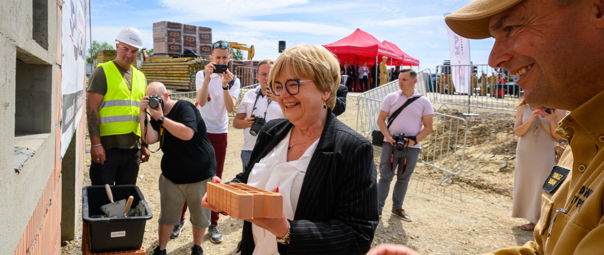 Zdjęcie przedstawia wojewodę podkarpackiego Teresę Kubas-Hul i komendanta wojewódzkiego straży Tomasza Barana podczas uroczystości wmurowania kamienia węgielnego pod budowę Podkarpackiego Centrum Ratownictwa i Koordynacji Transgranicznych Działań Ratowniczych