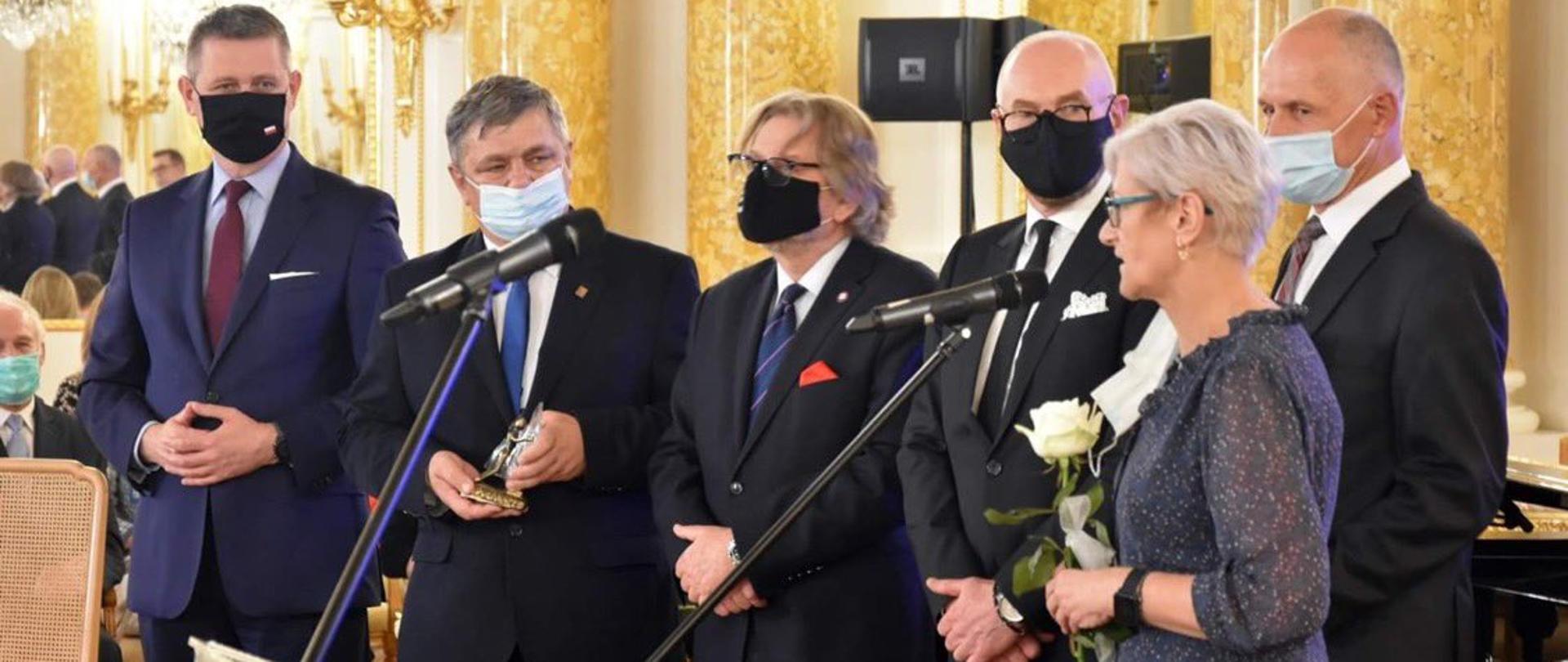 Elegancko ubrana kobieta oraz pięciu elegancko ubranych mężczyzn słucha przemawiającej kobiety podczas Gali Finałowej Jubileuszowej XV edycji Konkursu Lodołamacze 2020 r. 