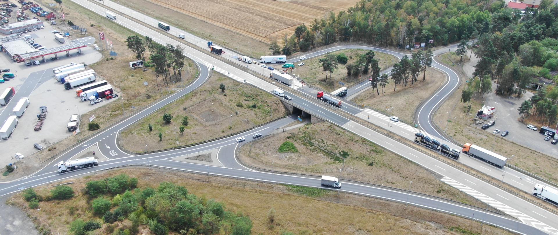 na zdjęciu widoczny węzeł autostradowy, po którym poruszają się pojazdy, W tle parkingi i samochody 