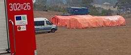 Na zdjęciu widać cztery namioty pneumatyczne koloru pomarańczowego z napisem Państwowa Straż Pożarna na białym tle.
Na pierwszym planie po lewej stronie widać tył samochodu gaśniczego straży pożarnej. W dalszym kadrze samochód Policji.