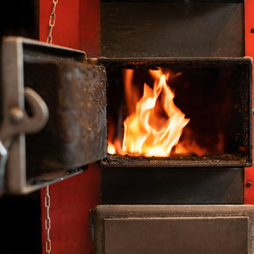 W otwartych drzwiczkach piecyka widać płonący ogień.