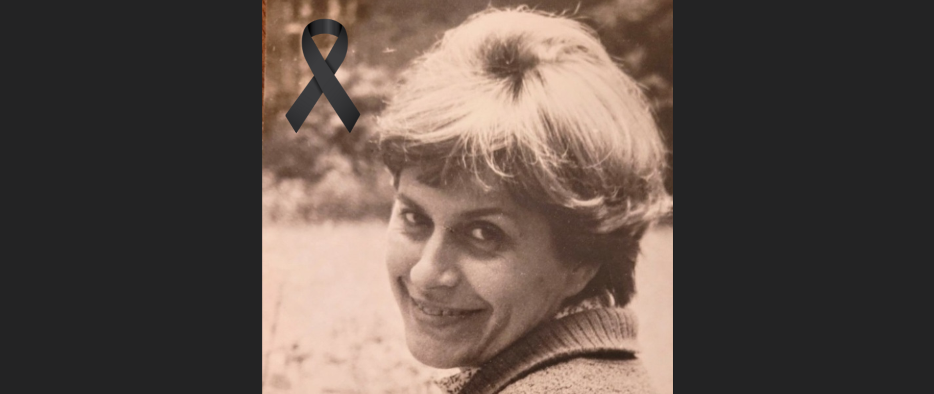 Pośrodku czarnego tła zdjęcie w sepii, twarz kobiety, bardzo pogodny uśmiech, włosy średniej długości. Spojrzenie przez lewe ramie. Tło rozmyte. W lewym górnym rogu skrzyżowana czarna wstążka. 