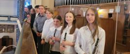 Pamiątkowe zdjęcie uczestników koncertu organowego w kościele parafialnym Najświętszego Serca Pana Jezusa w Gdyni. Na fotografii uczniowie szkół muzycznych wraz z pedagogami pozują na tle prospektu organowego; część uczestników trzyma instrumenty – oboje i trąbkę.