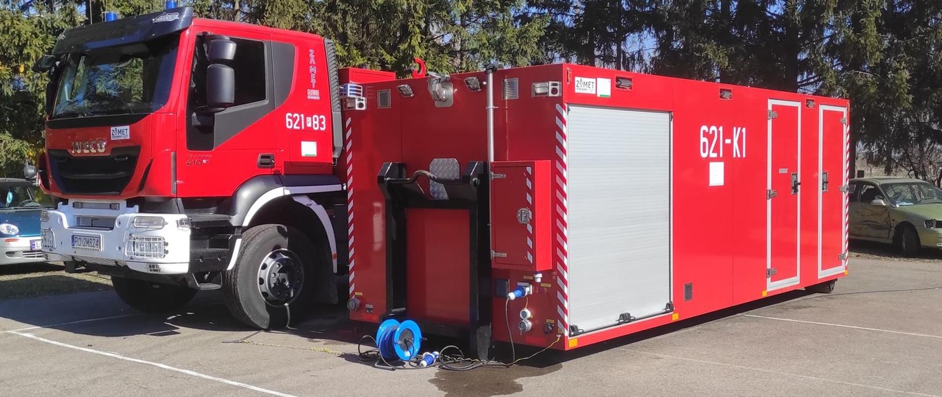 Pojazd pożarniczy i kontener sanitarny obok. 