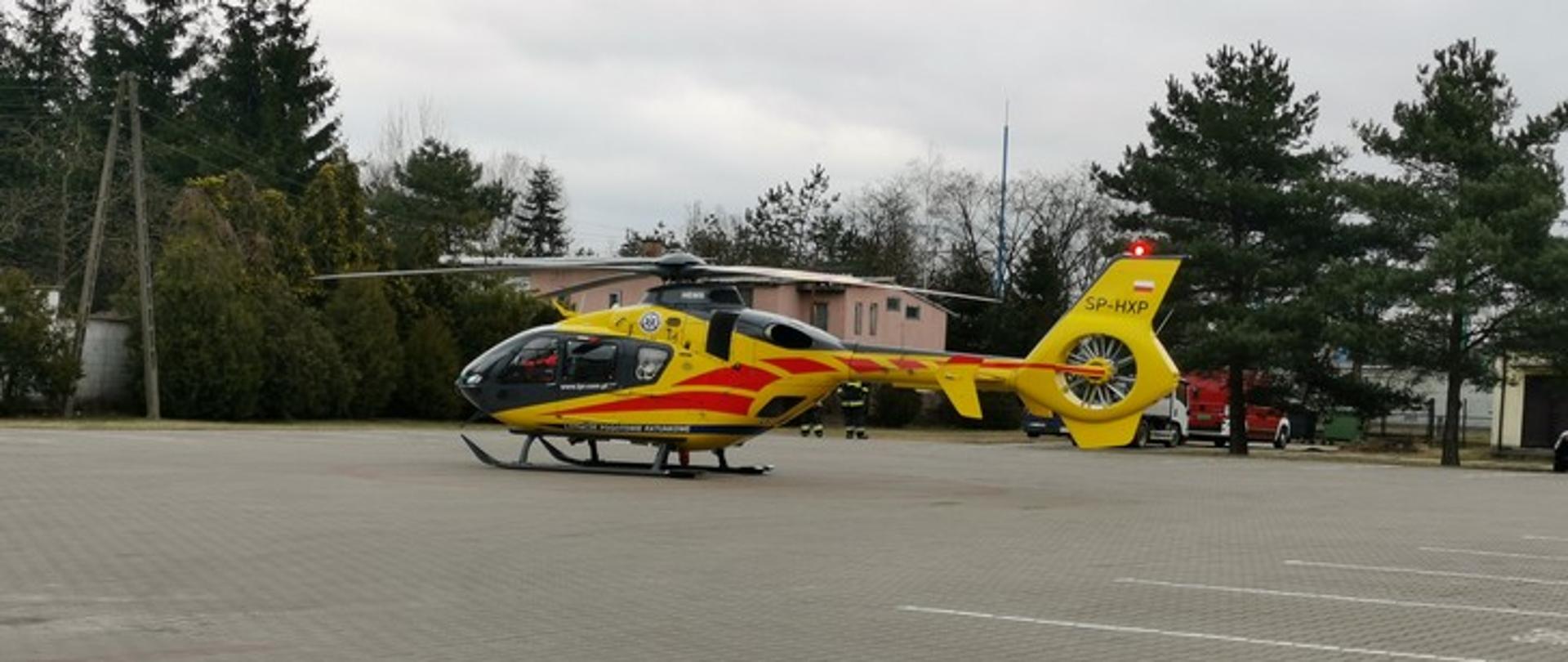 Zdjęcie przedstawia śmigłowiec Lotniczego Pogotowia Ratunkowego w kolorze żółtym stojący na dużym placu.
