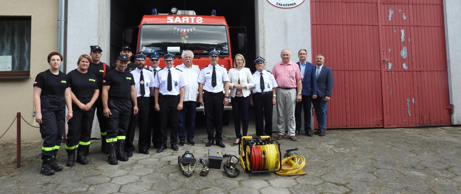Widać przedstawicieli władz samorządowych, strażaków, zestaw hydrauliczny, samochód strażacki na tle remizy OSP Bytyń