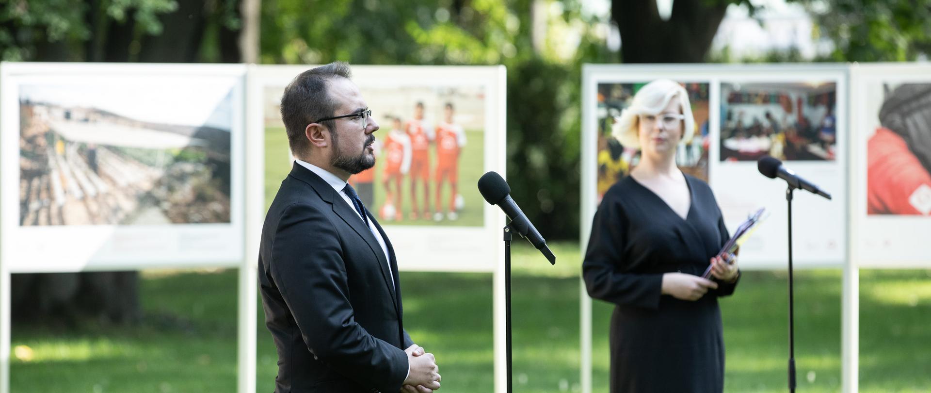 Mężczyzna i kobieta stojący na tle wystawy w ogrodach KPRM