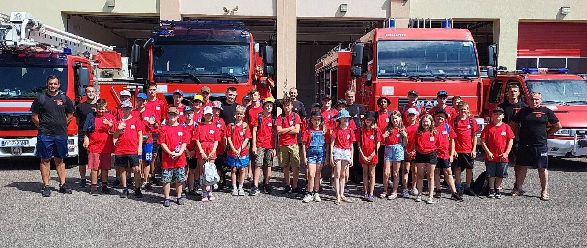 Uczestnicy obozu Młodzieżowych Drużyn Pożarniczych na tle samochodów pożarniczych