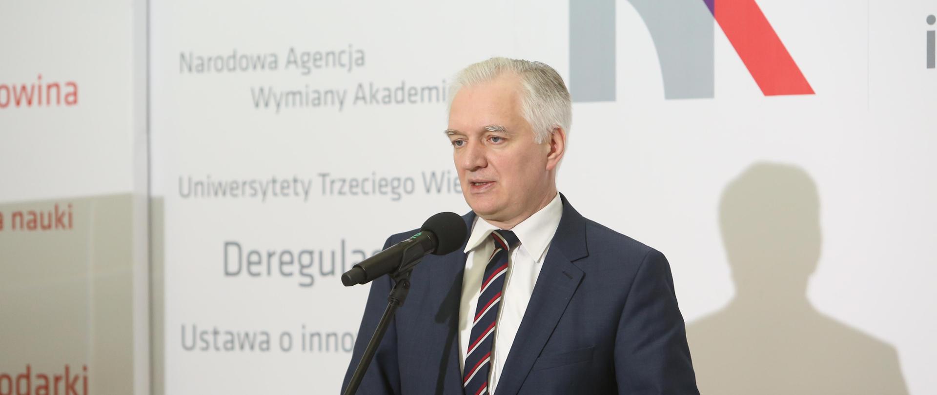 Minister Gowin na tle ściany z logiem MNiSW