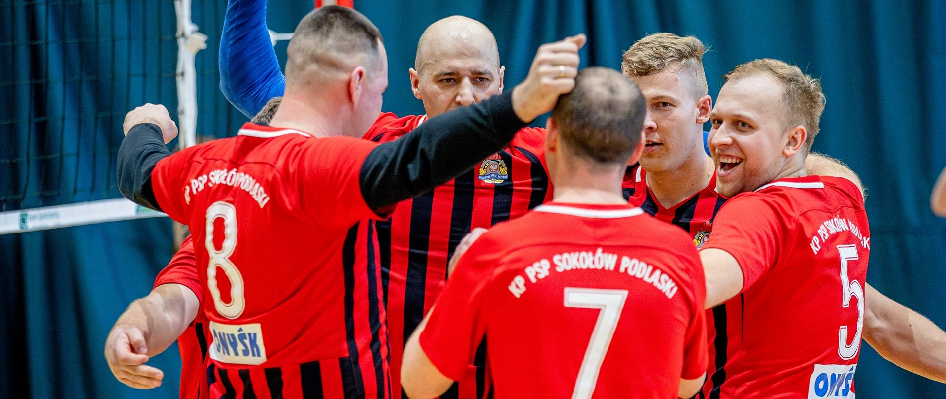 Zwycięstwo sokołowskich strażaków w eliminacjach do XXII Mistrzostwach Województwa Mazowieckiego Strażaków PSP w Piłce Siatkowej - na zdjęciu strażacy na sali gimnastycznej zbierają się w koło po zdobytym punkcie.