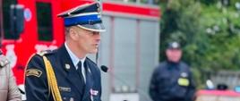 Komendant miejski PSP w Łomży w trakcie przemówienia. W tle widoczni pozostali goście uroczystości