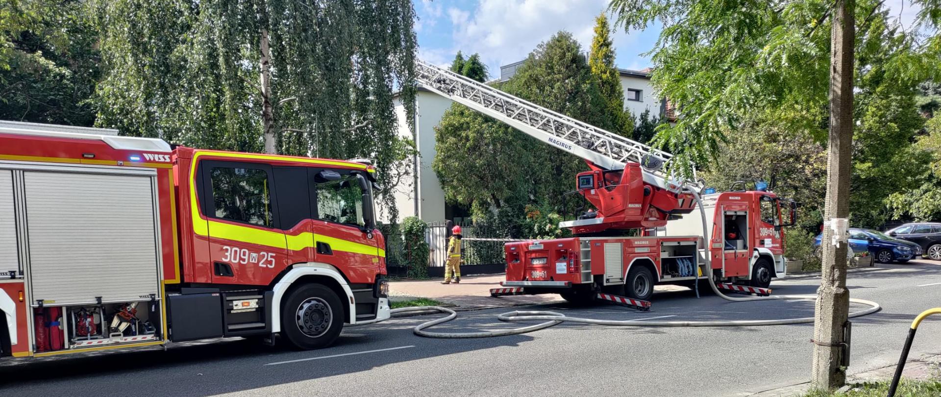 Na zdjęciu widoczne są samochody straży pożarnej oraz pracujący strażacy
