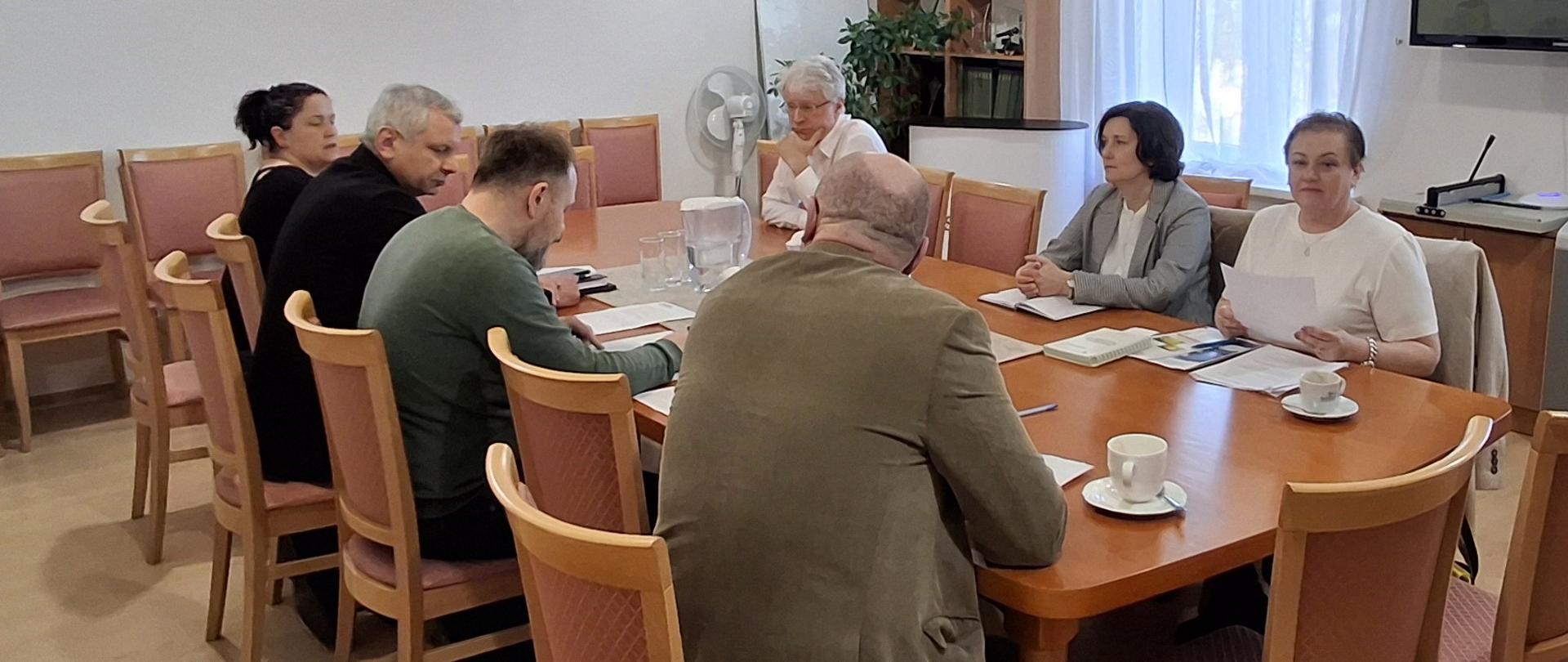 Grupa osób siedząca przy stole narad