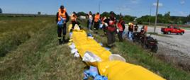  Strażacy podwyższają koronę wału przeciwpowodziowego przy użyciu rękawów przeciwpowodziowych