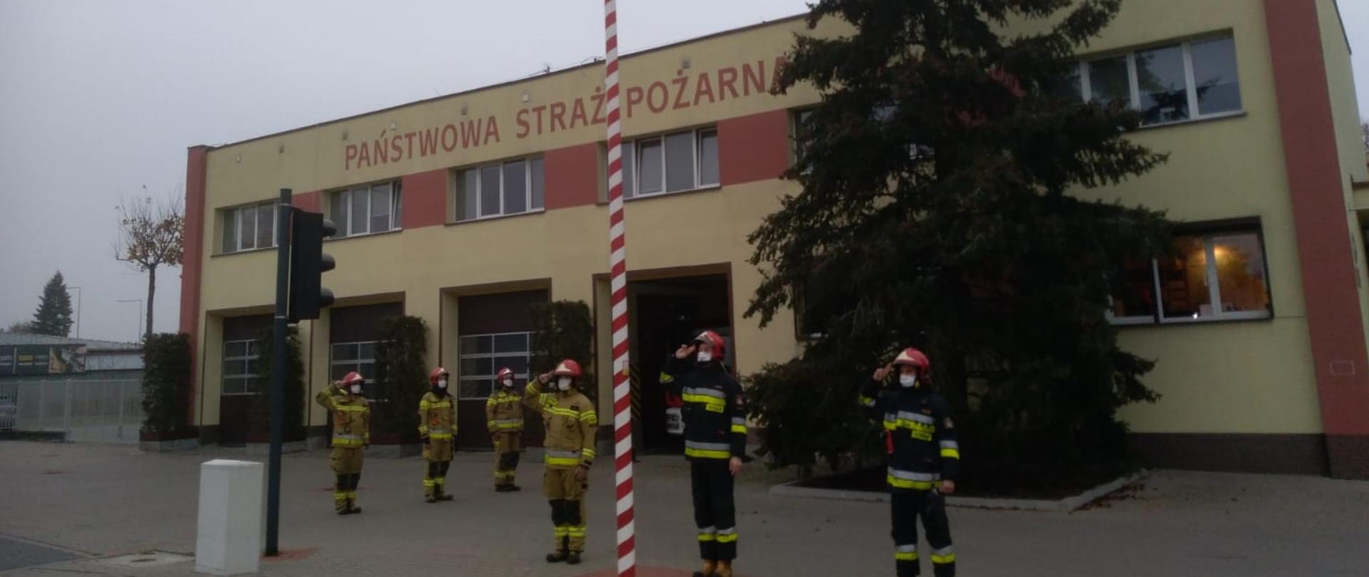 Na zdjęciu widać strażaków oddających honory fladze państwowej 