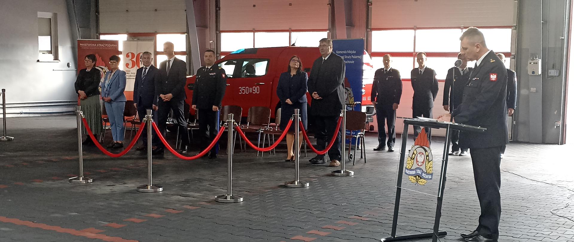 Zdjęcie przedstawia Komendanta Miejskiego Państwowej Straży Pożarnej w Częstochowie otwierającego uroczystość wręczenia promes dotacji celowej dla Ochotniczych Straży Pożarnych na zakup sprzętu dla członków Młodzieżowych Drużyn Pożarniczych na tle trybuny honorowej