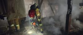 Na zdjęciu widać wnętrze spalonego poddasza oraz strażaków 