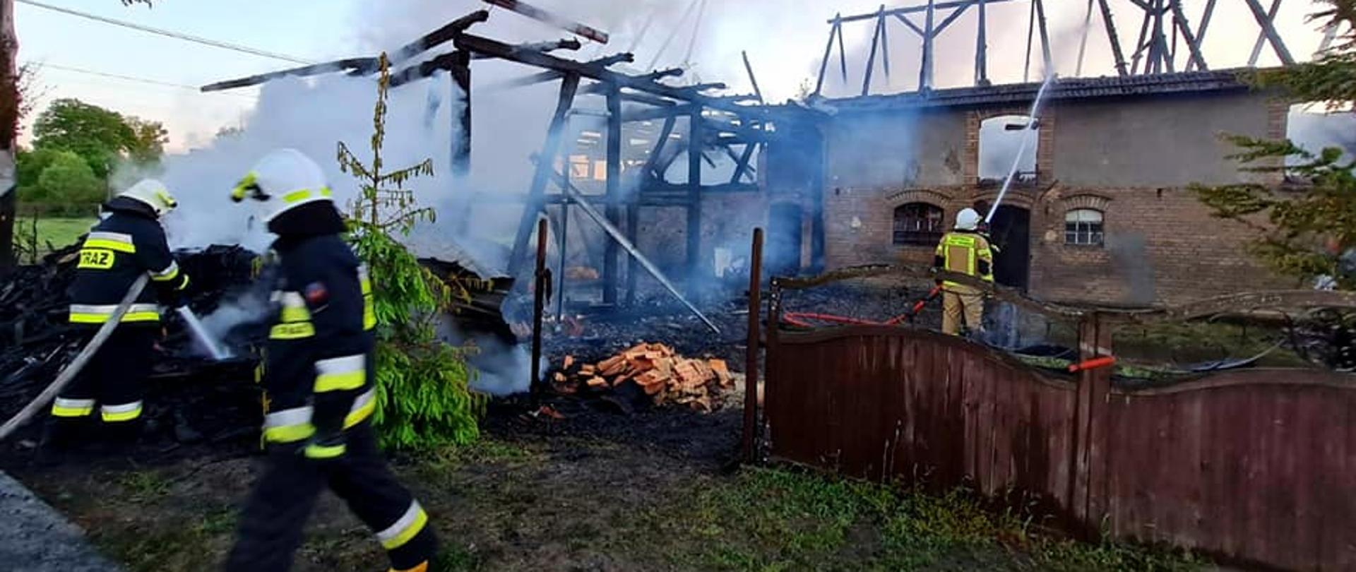 Zdjęcie przedstawia palącą się stodołę w Starkowie. Na pierwszym planie ratownicy biorący udział w akcji.