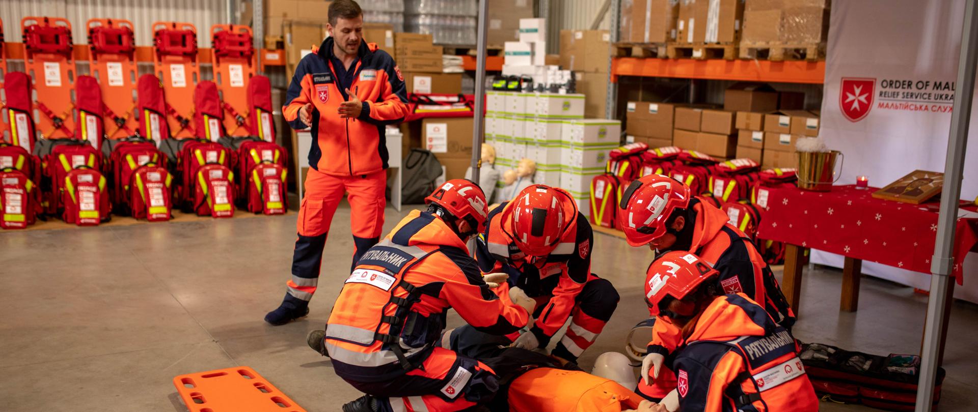 Strażacy w pełnym stroju ćwiczą pierwszą pomoc na fantomie