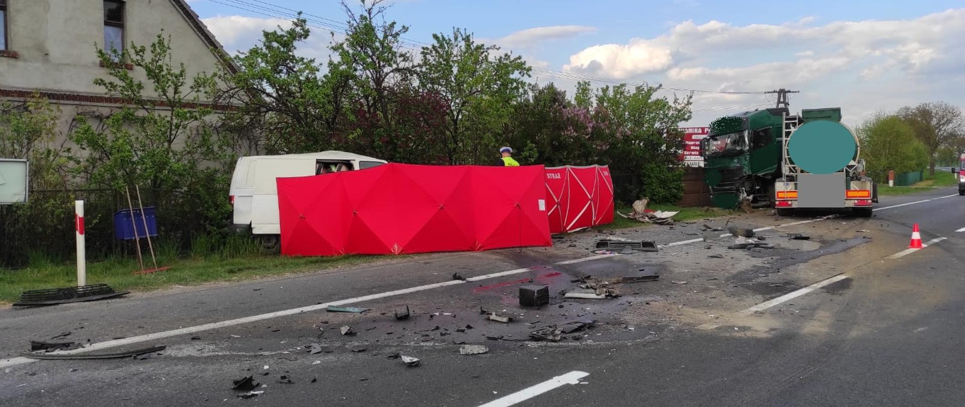 Widać uszkodzony samochód ciężarowy, po lewej parawan straży pozarnej