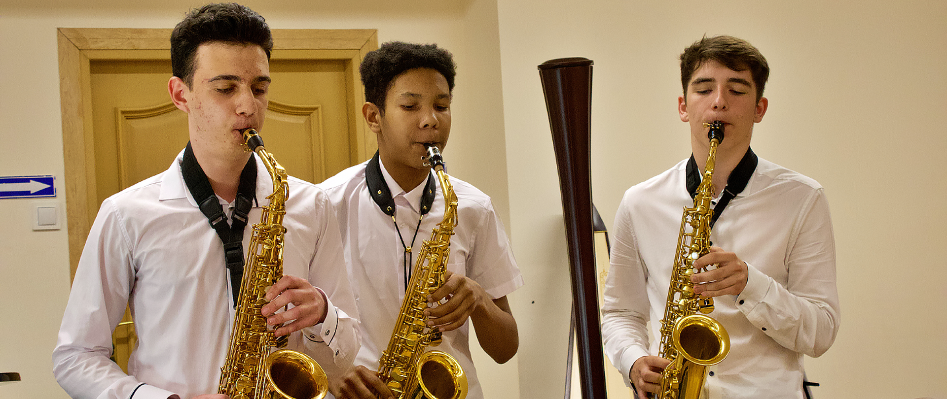 Na zdjęciu trzech chłopców gra na saksofonach.