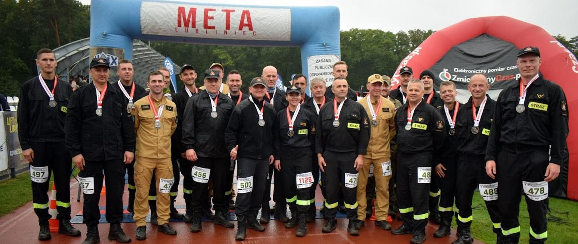 Funkcjonariusze i funkcjonariuszki PSP reprezentujący województwo mazowieckie z pamiątkowymi medalami po ukończeniu biegu w tle linia mety