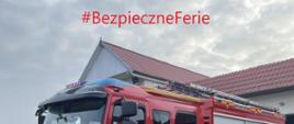 Zdjęcie przedstawia pojazd ratowniczo-gaśniczy koloru czerwonego oraz napis "Wpadnij do Strażnicy" w ramach akcji bezpieczne ferie.