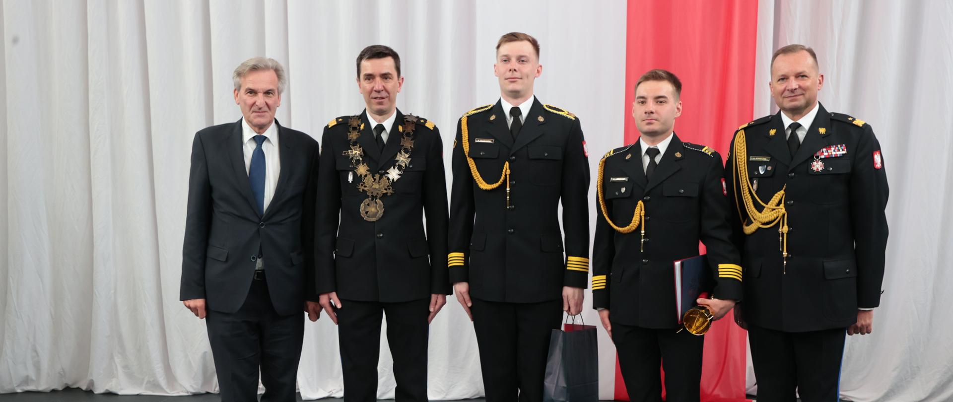 Mężczyzna w ubraniu cywilnym i 4 funkcjonariuszy PSP stoją w rzędzie pozując do zdjęcia