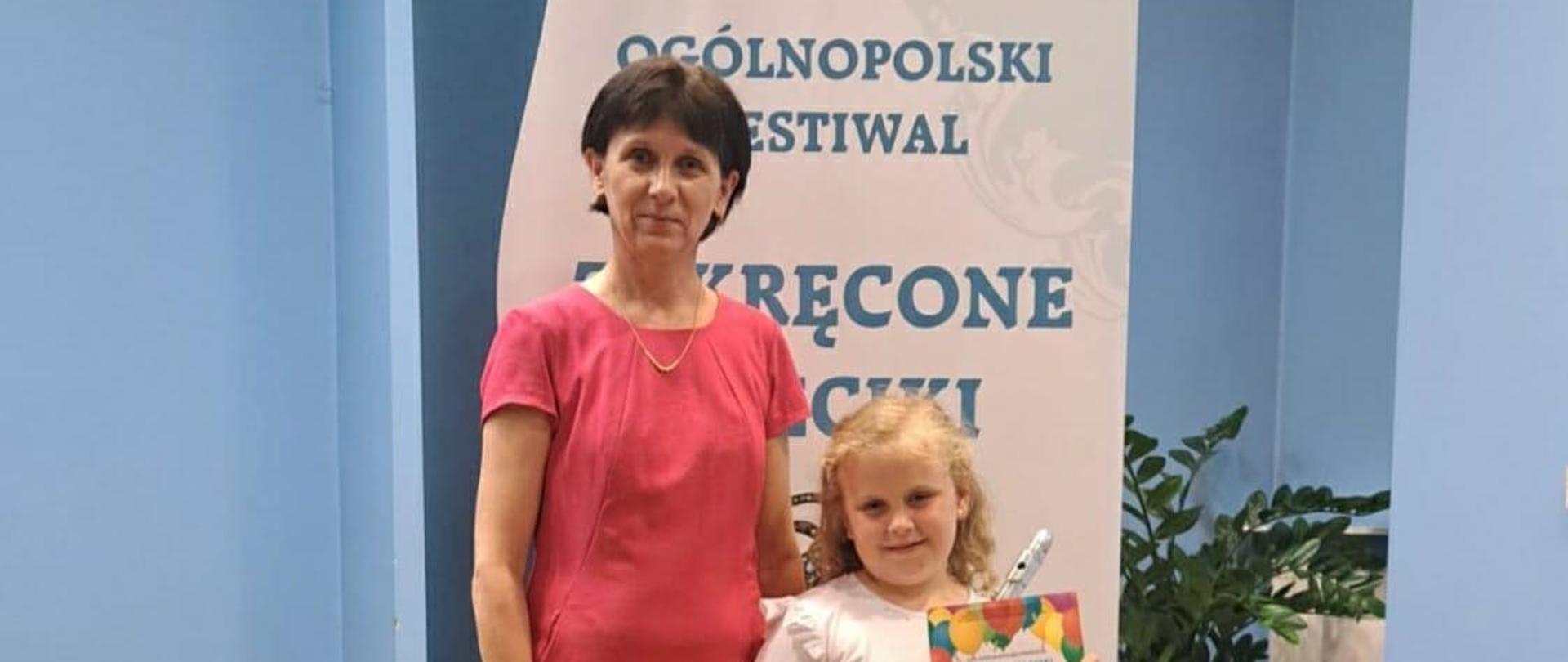 Zdjęcie przedstawia panią nauczycielkę ora uczennicę z instrumentem i dyplomem w rękach. 