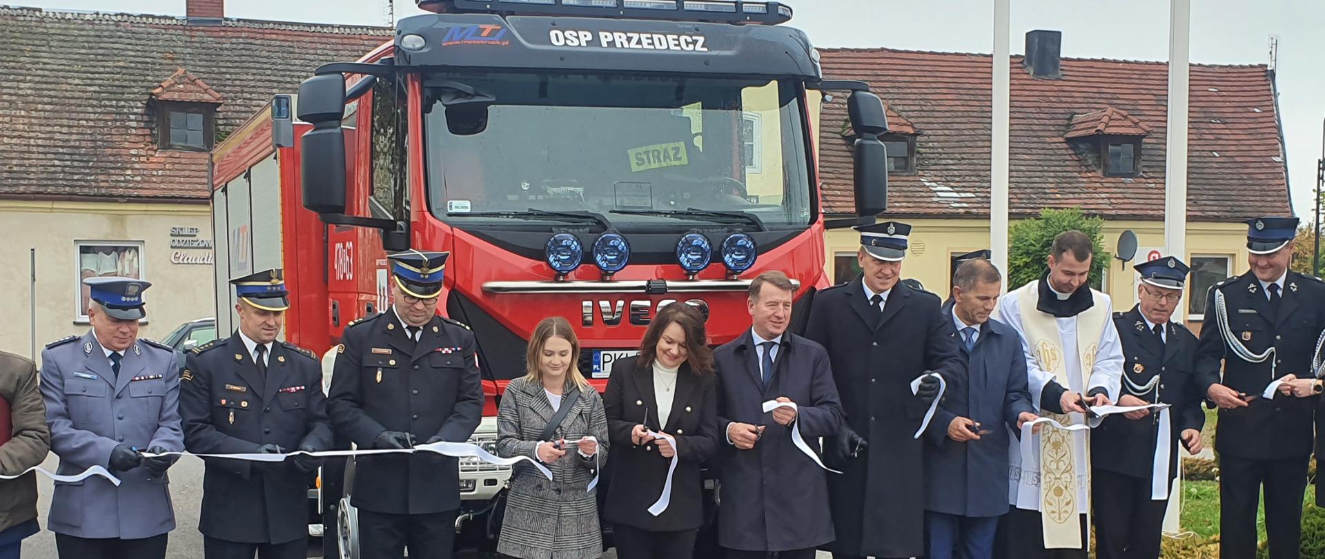 Zdjęcie przedstawia zaproszonych gości podczas przecięcia wstęgi przy nowopozyskanym samochodzie ratowniczo-gaśniczym dla jednostki OSP Przedecz