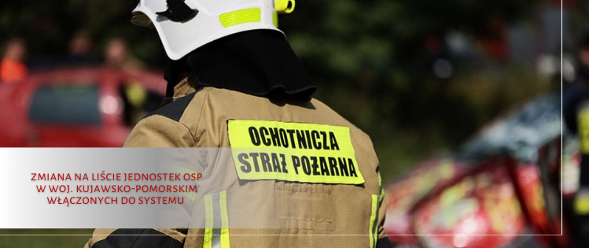 Strażak w ubraniu specjalnym z białym hełmem na głowie. Stoi odwrócony tyłem.