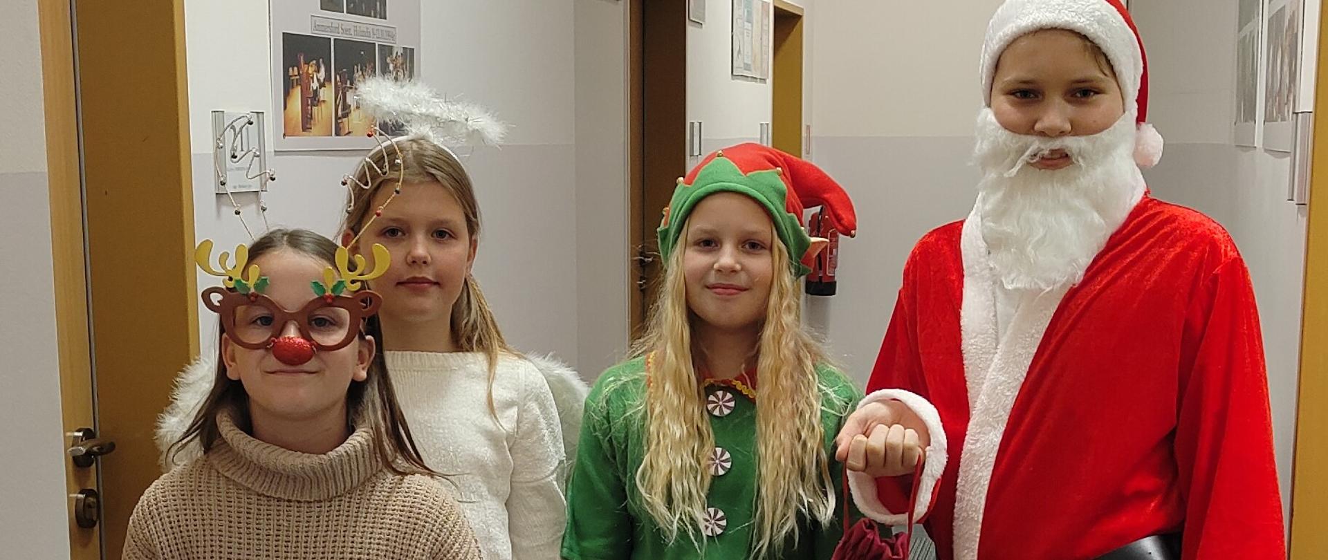 Zdjęcie 4 uczniów przebranych w stroje mikołajkowe - elf, anioł, renifer i Mikołaj