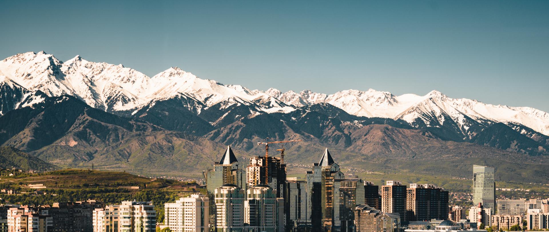 City landscape on a background of snow-capped Tian Shan mountains. The complex of buildings along Al-Farabi avenue. Photo taken in Almaty, Kazakhstan.