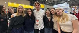Słodkie inspiracje i nowe doświadczenia – uczniowie gastronomii na Expo Sweet pozują do zdjęcia z Karolem Okrasą