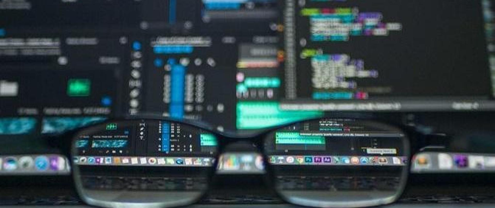 Grafika - okulary na tle monitorów komputerowych