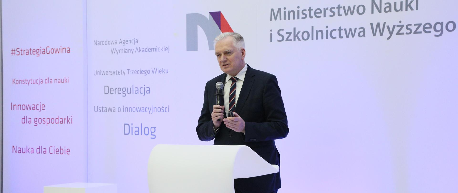 Minister Gowin przemawia na tle ściany z logiem MNiSW