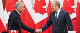 Premier Donald Tusk i Premier Kanady Mark Carney podczas wspólnego oświadczenia w Kancelarii Prezesa Rady Ministrów. W tle flagi obu państw.