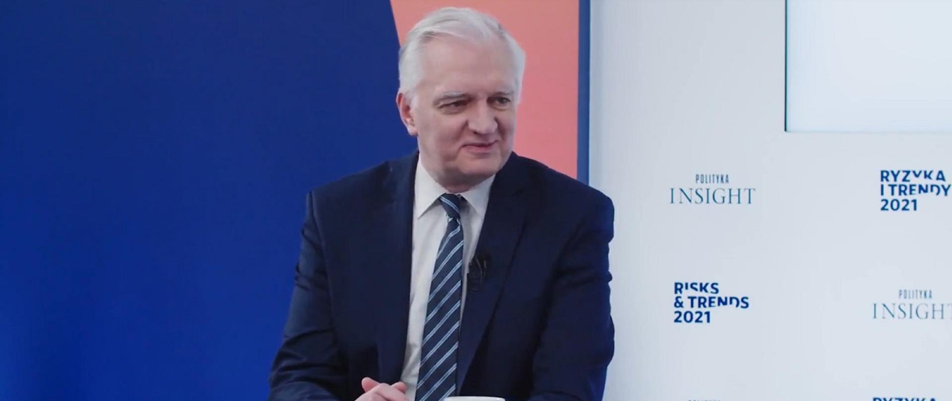 Wicepremier, minister rozwoju, pracy i technologii Jarosław Gowin siedzący przy stole, z tyły za jego plecami banner Polityka Insight
