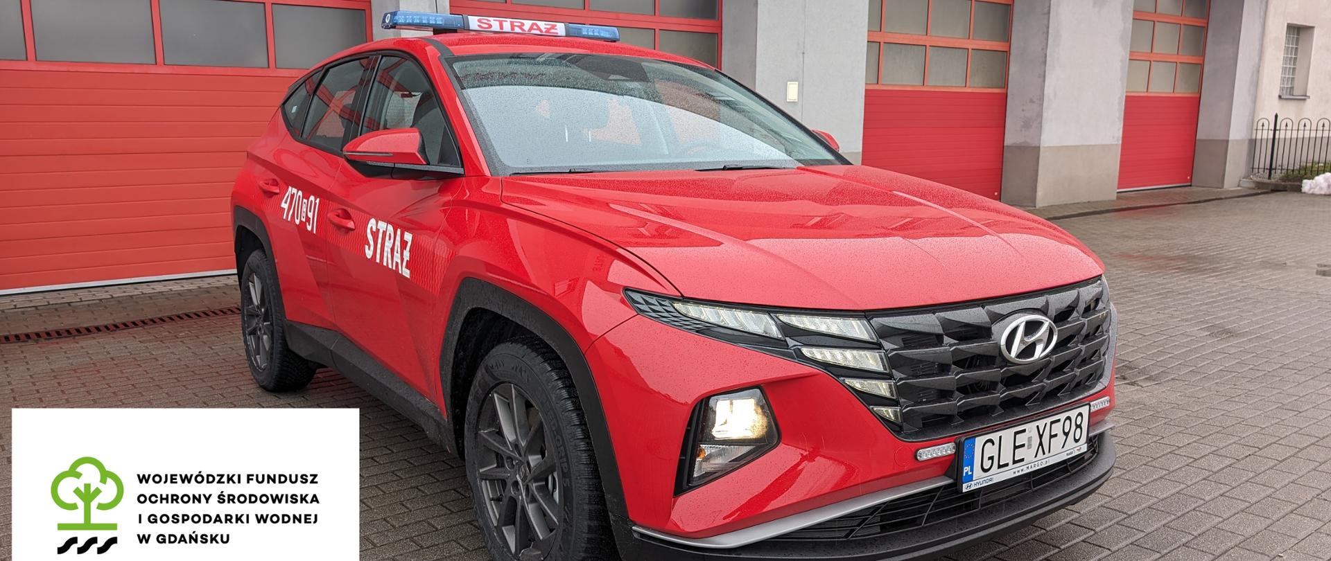 Zdjęcie pokazowe samochodu HYundai Tucson przodem przez budynkiem komendy oraz logotyp Wojewódzkiego Funduszu Ochrony Środowiska i Gospodarki Wodnej w Gdańsku