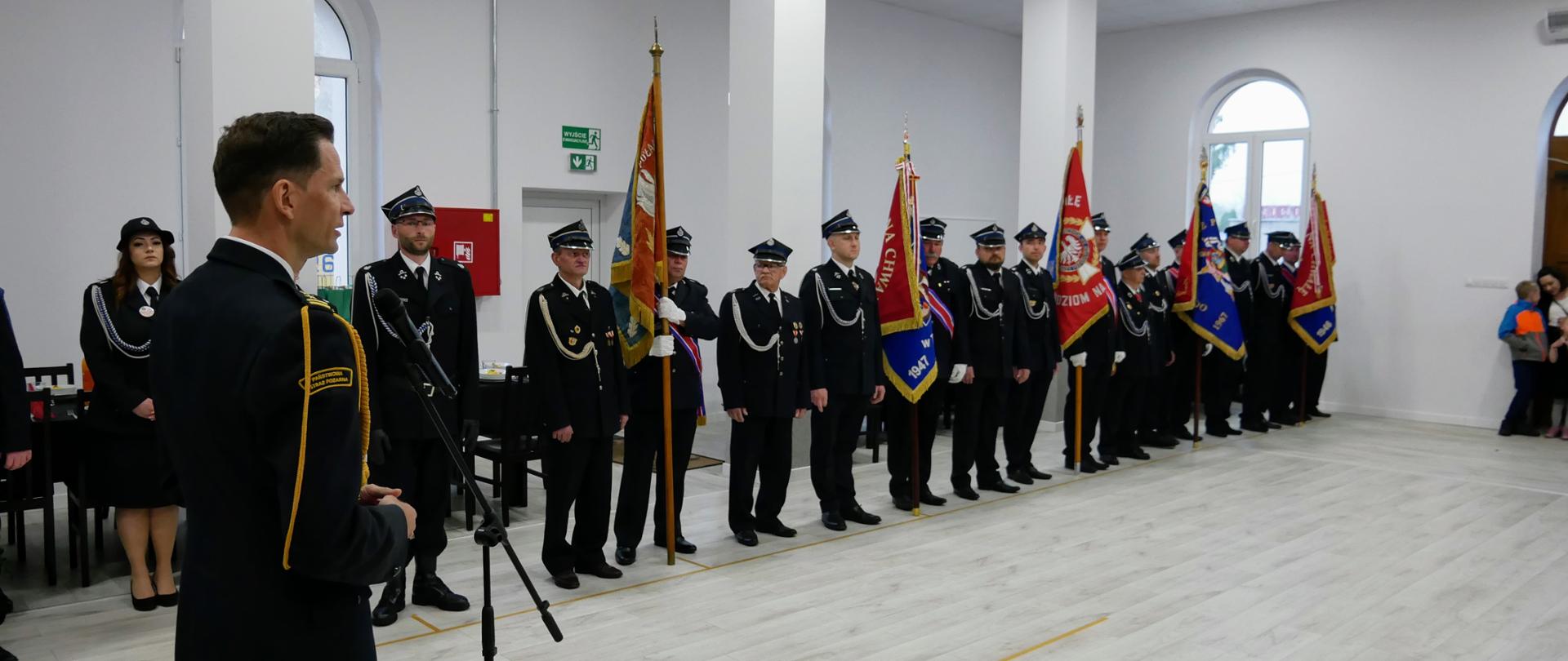 75-lecia Ochotniczej Straży Pożarnej w Niwicy - zastępca LKW przemawia na pierwszym planie w tle stoja poczty sztandarowe