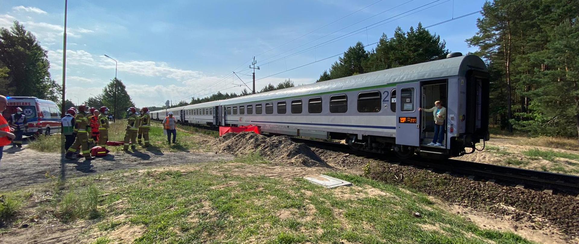 Dzień. Słonecznie. Na zdjęciu widnieje stojący pociąg, który potrącił rowerzystę. Bez opadów deszczu. 