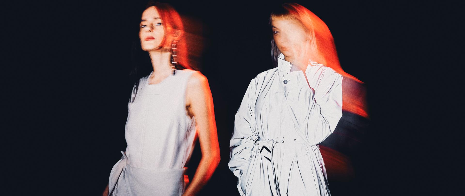 Portret dwóch kobiet w bieli na czarnym tle.