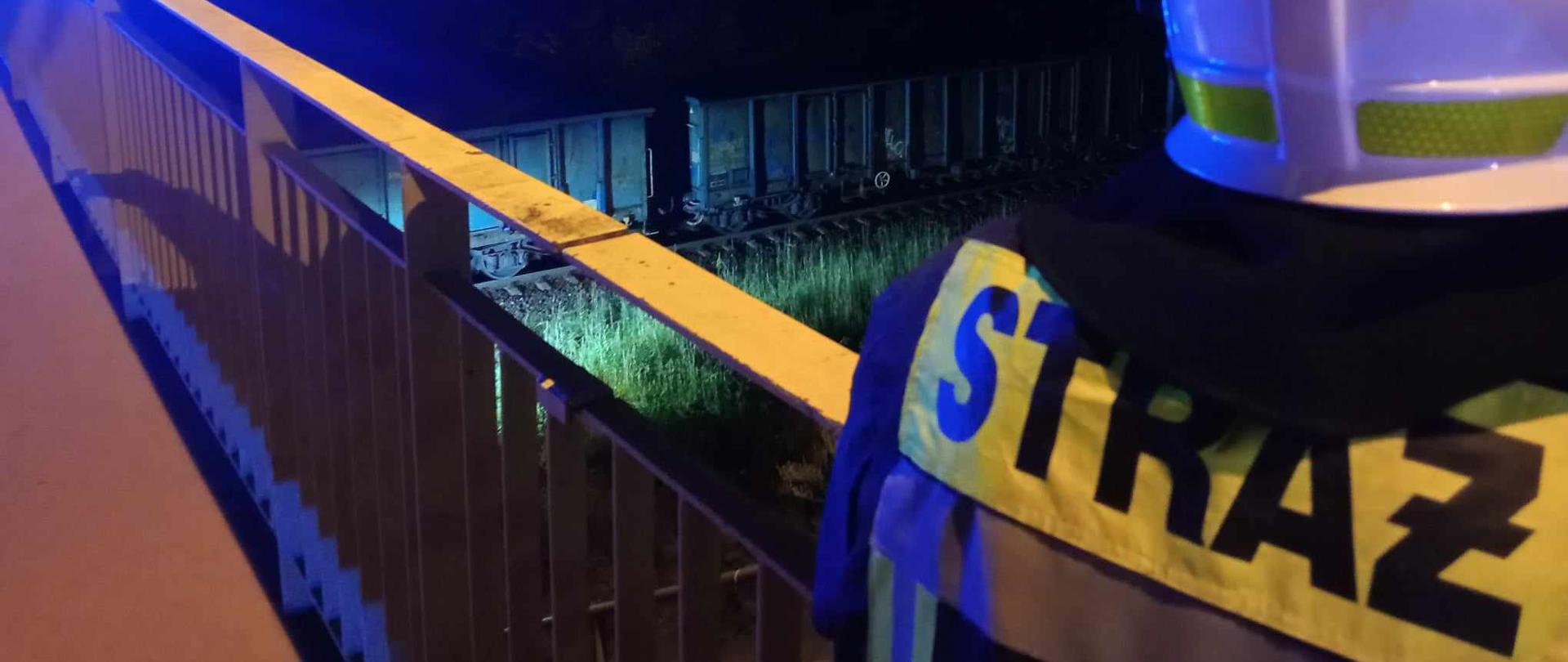 Zdjęcie przedstawia strażaków i stojący pociąg z powodu śmiertelnego potrącenia mężczyzny.
W tle tereny zielone.
