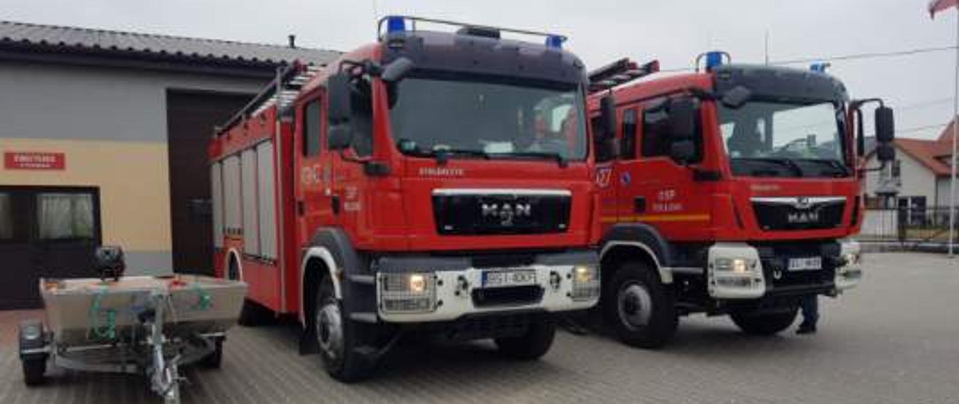 Zdjęcie strażnicy OSP Perlejewo. Przed garażem stoją dwa samochody pożarnicze oraz łódź motorowa