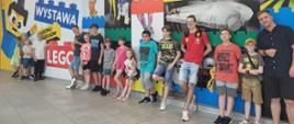 Grupa uczniów wraz z nauczycielem Tomasz Brusińskim stojąca przy wystawie klocków lego